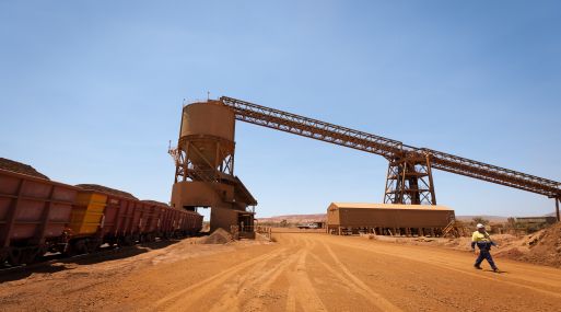 A mine worker walks past a train loader at Rio Tinto Group's West Angelas iron ore mine in Pilbara, Australia, on Sunday, Feb. 19, 2012. Rio Tinto Group, the world's second-biggest iron ore exporter, will spend $518 million on the first driverless long-distance trains to haul the commodity from its Western Australia mines to ports, boosting efficiency. Photographer: Ian Waldie/Bloomberg